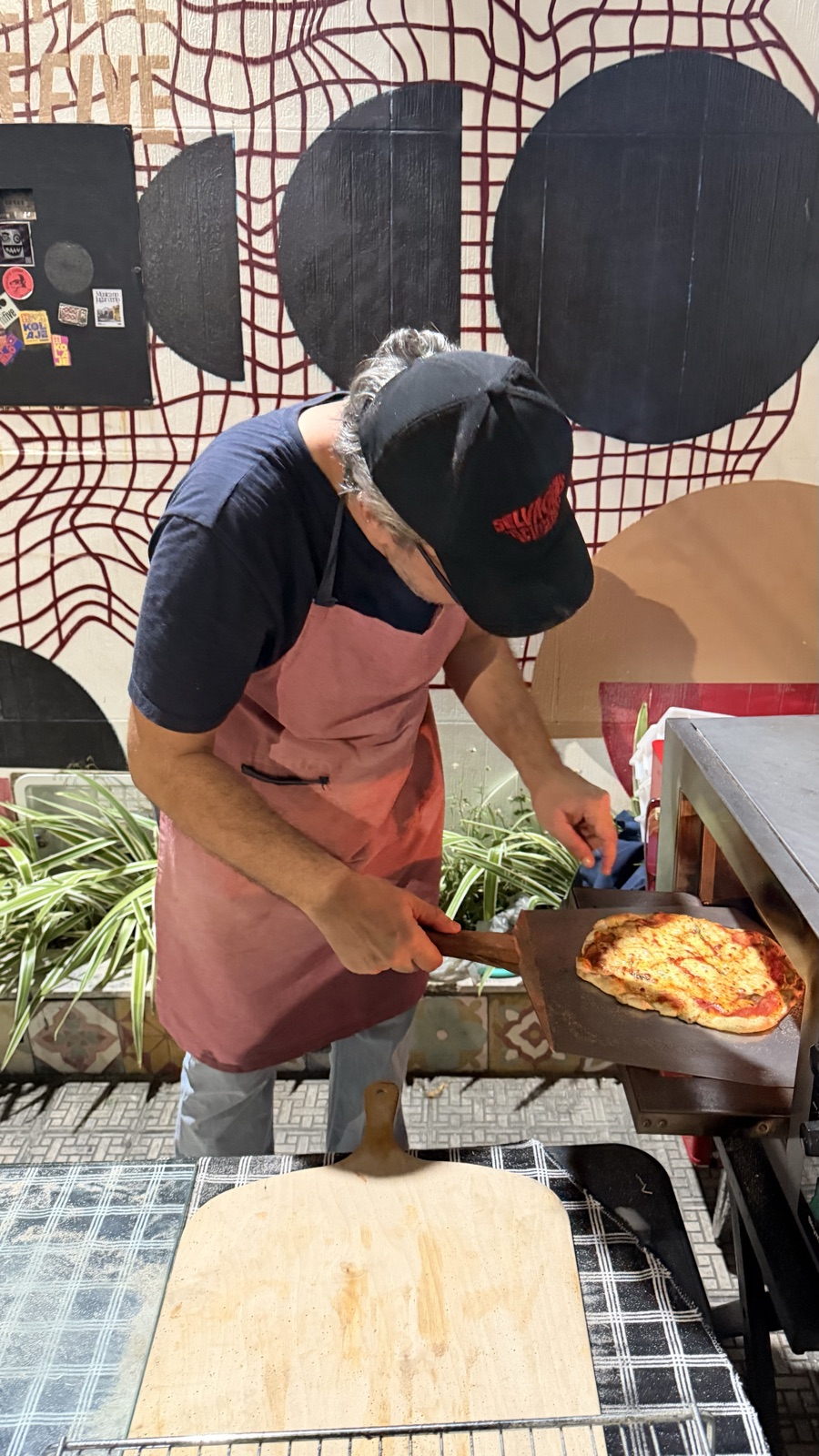 Pizza entrando no forno na pá de madeira