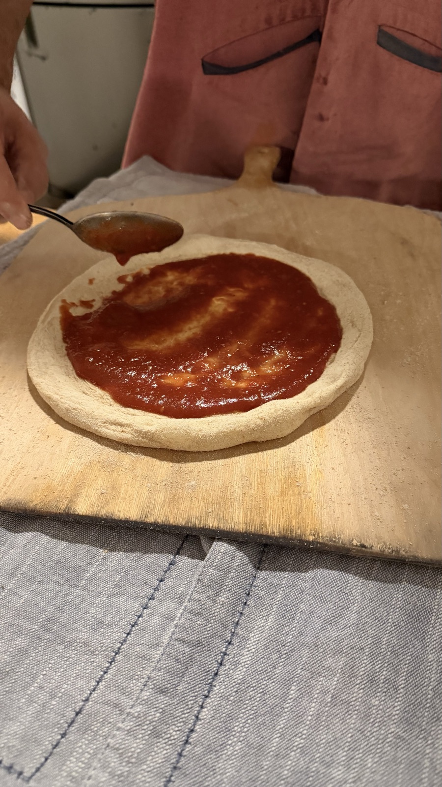Molho de tomate sendo espalhado na massa com colher