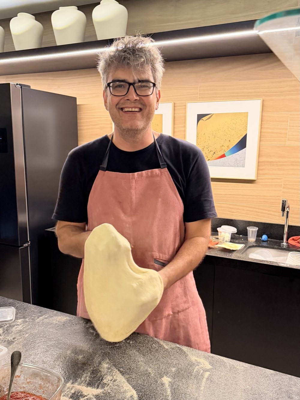 O pizzaiolo da Tomolino sorrindo, segurando um disco de massa aberto à mão